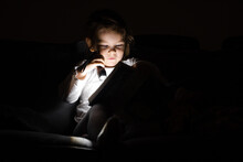 Toddler Caucasian Girl Reading Book At Hight With Flashlight. Unplugged Childhood Activities. Goodnight Bedtime Routine. Reading Fantasy Farytale