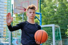 Serious Guy Teenager With Basketball Ball Showing Stop Sign Hand Gesture