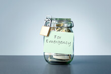 For Emergency Savings Written On The Jar With Dollars Banknotes Money. Concept Of Money Saving For Rainy Day.