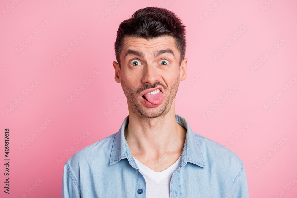 Photo portrait of silly crazy tricky guy showing tongue grimacing isolated pastel pink color background - obrazy, fototapety, plakaty 