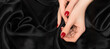 Female hands with red nail design. Red nail polish manicure. Woman hands on black fabric background. Copy space.