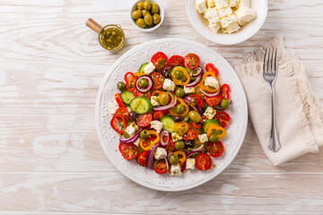 Wall Mural - Greek salad of fresh cucumber, tomato, sweet pepper, red onion, feta cheese and olives with olive oil dressing