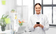 © Syda Productions - medicine, profession and healthcare concept - happy smiling female doctor with stethoscope using smartphone over medical office at hospital on background