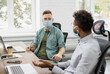 © kite_rin - Working moments. Group of young coworkers people discussing business ideas while working in the office. Colleagues have discussion wearing medical protective masks, social distancing concept
