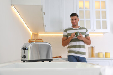 Canvas Print - Man preparing breakfast in kitchen, focus on toaster with slices of bread