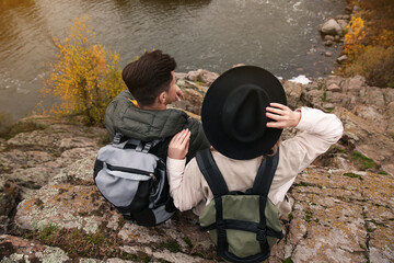 Sticker - Couple of travelers with backpacks enjoying beautiful view near mountain river. Autumn vacation