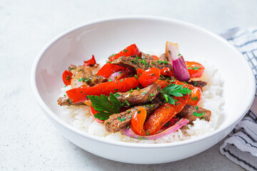 Wall Mural - Fried beef with vegetables and rice in white plate. Stir fry beef with peppers and onions, served with rice.