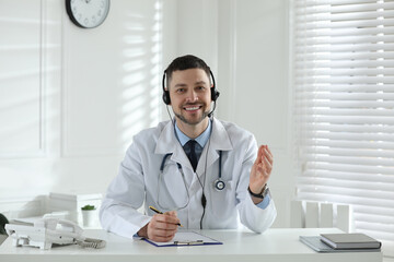 Poster - Doctor with headset consulting patient over phone at desk in clinic. Health service hotline