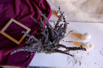 bunch of lavender in glass vase on a white background across picture frame, purple blanket, candles. Top view. Home decor. interior design