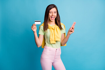 Wall Mural - photo of funny positive person eye wink hold phone debit card good mood isolated on blue color backg