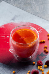 Poster - Grapefruit herbal tea with spices and honey in glass cup on a grey background, red hot drink with orange, a Japanese traditional drink