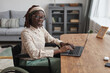 © Seventyfour - Portrait of young African-American woman using wheelchair and looking at camera while working from home in minimal grey interior, copy space