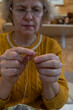 © Barillo_Images - Middle aged woman wearing glasses trying carefully to thread a needle.