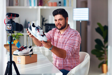 young adult man selling, promoting shoes online at his home office, working from home, content creator