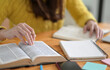 © sarawutnirothon - Close up shot of Young women wearing yellow clothes are reading books to prepare for college entrance exams.