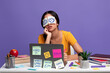 Tired indian woman sitting at desk with sticky notes