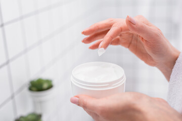 Wall Mural - partial view of woman holding jar with face cream