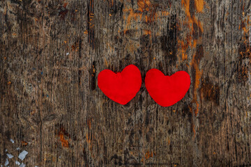 Poster - Valentine's day, two red fabric hearts lie on a dark textured wooden board