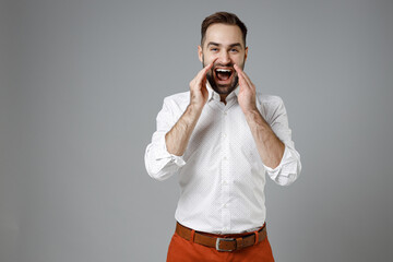 Wall Mural - Cheerful excited young bearded business man 20s wearing classic white shirt scream news with hands near mouth isolated on grey color wall background studio portrait. Achievement career wealth concept.