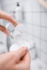 Wall Mural - close up of woman holding bottle with toner and cotton pad in bathroom