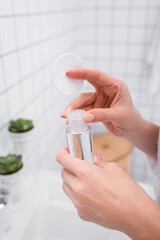 Wall Mural - partial view of woman holding toner and cotton pad in bathroom