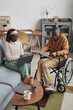 © Seventyfour - Vertical full length portrait of African-American couple with handicapped man working from home together in modern interior