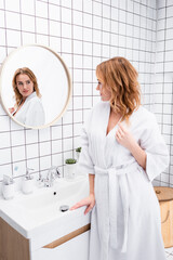 Wall Mural - woman in white bathrobe looking at mirror in bathroom