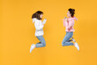 © ViDi Studio - Full length side view of happy two young women friends 20s wearing basic white pink hoodies jumping doing winner gesture celebrating say yes isolated on bright yellow color background studio portrait.