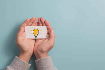 Businessman holding white paper with lightbulb glowing drawing on hand for creative thinking idea and innovative technology concept.