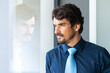© Joao - Businessman looking through window. Successful male portrait at the office with the right focus, serious and serene attitude.