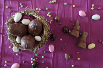 Wall Mural - Top view of nest with chocolate eggs, chocolate rabbits and easter almonds on table