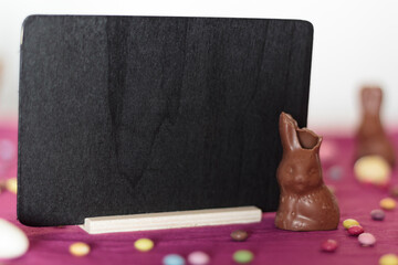 Canvas Print - Chocolate bunny missing a bite and blackboard with copy space