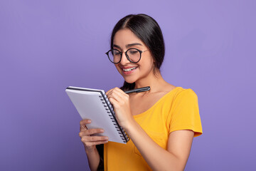 Woman holding pen writing in notebook at studio