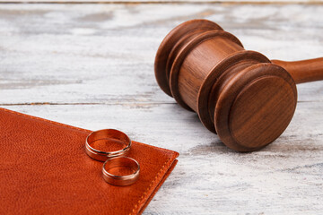 Judge gavel and wedding rings. White wood background.