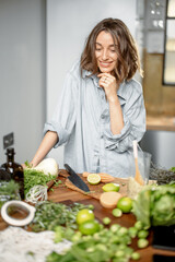 Pretty woman with green ingredients thinking about cooking healthy food on the kitchen. Healthy and wellness concept. High quality photo