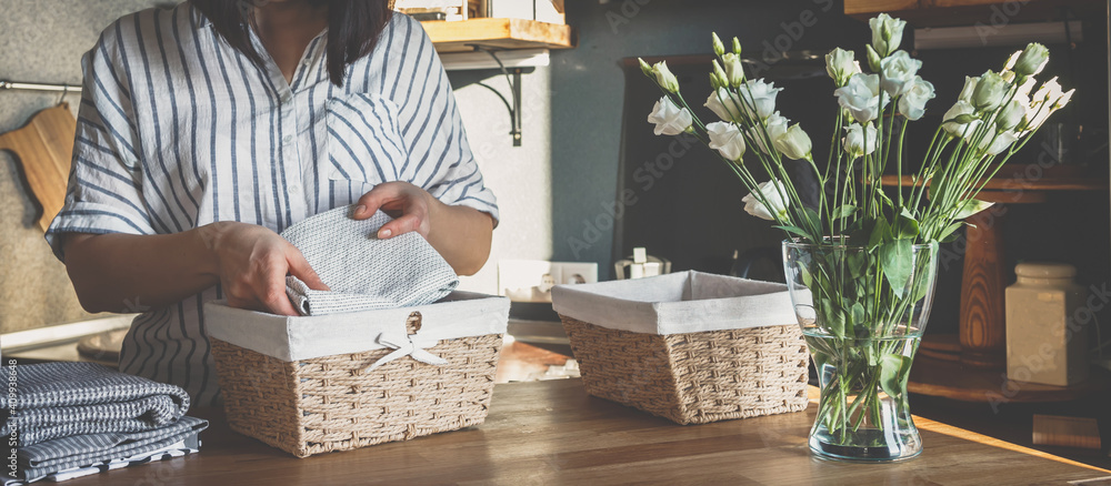 Girl spring cleaning in the kitchen. Piles kitchen towels in baskets. Spring cleaning, decluttering, cleaning space, cleaning agency - obrazy, fototapety, plakaty 