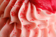 Close up macro texture of pink cupcake icing with red sprinkles for valentines day dessert concept.