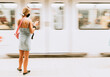 © Alex Bascuas/ADDICTIVE STOCK - Back view of unrecognizable young female passenger in casual outfit and black protective mask standing on platform of subway station and checking information on mobile phone