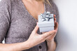 © Alla Machutt/ADDICTIVE STOCK - Unrecognizable crop female standing with Christmas present in gift box on white background in studio