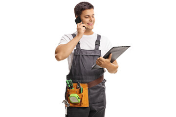 Repairman in a uniform holding a clipboard and talking on a mobile phone