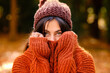 © Antonio Ovejero/ADDICTIVE STOCK - Young female in knitted hat covering face with warm sweater while standing in forest in cold autumn day