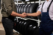© alfa27 - salesman and customer shaking hands in auto service shop, male made choice, buying car tire for winter