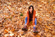 © Antonio Ovejero/ADDICTIVE STOCK - From above full length of cheerful young female in red knitted sweater and jeans sitting on fallen leaves and enjoying sunny autumn day in forest