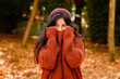 © Antonio Ovejero/ADDICTIVE STOCK - Young female in knitted hat covering face with warm sweater while standing in forest in cold autumn day