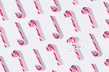 Top View Full Frame Composition Of Red And White Striped Xmas Candy Canes Arranged In Rows With One Cane Broken On White Background