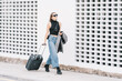© Carlos Rodelas/ADDICTIVE STOCK - Stylish female tourist with suitcase walking along street in city and looking away