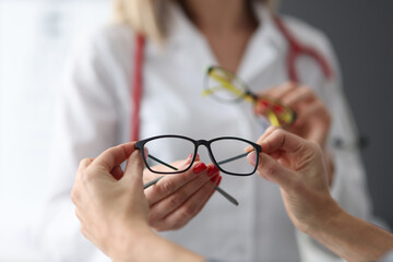 Canvas Print - Ophthalmologist offering patient glasses for vision in clinic closeup