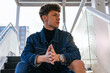 © David Munoz/ADDICTIVE STOCK - Determined young male model in denim outfit sitting on staircase in street and looking away