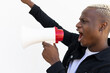 © David Munoz/ADDICTIVE STOCK - Side view of cheerful African American male shouting in loudspeaker while standing with fist up on white background