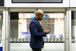 © David Munoz/ADDICTIVE STOCK - Side view of serious African American businessman standing in subway train and messaging on smartphone while commuting to work